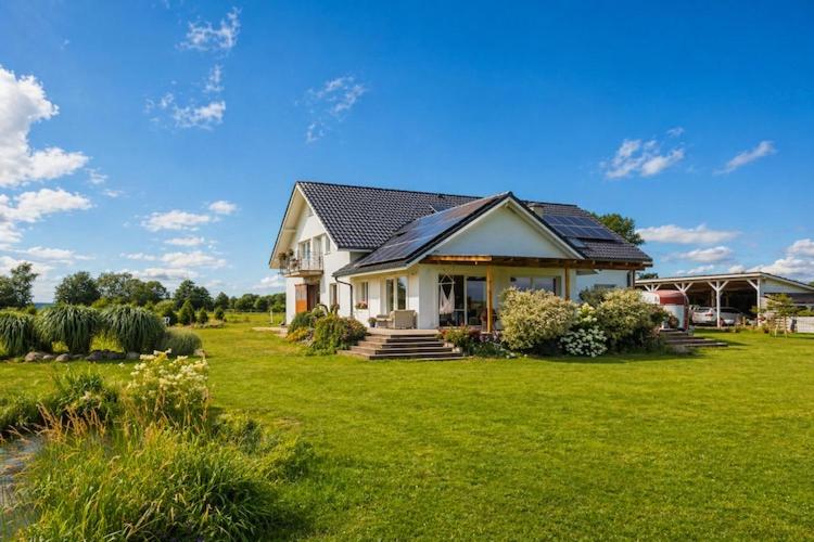 a house on a lawn with a green yard at Agritourism by the sea in Ładzin
