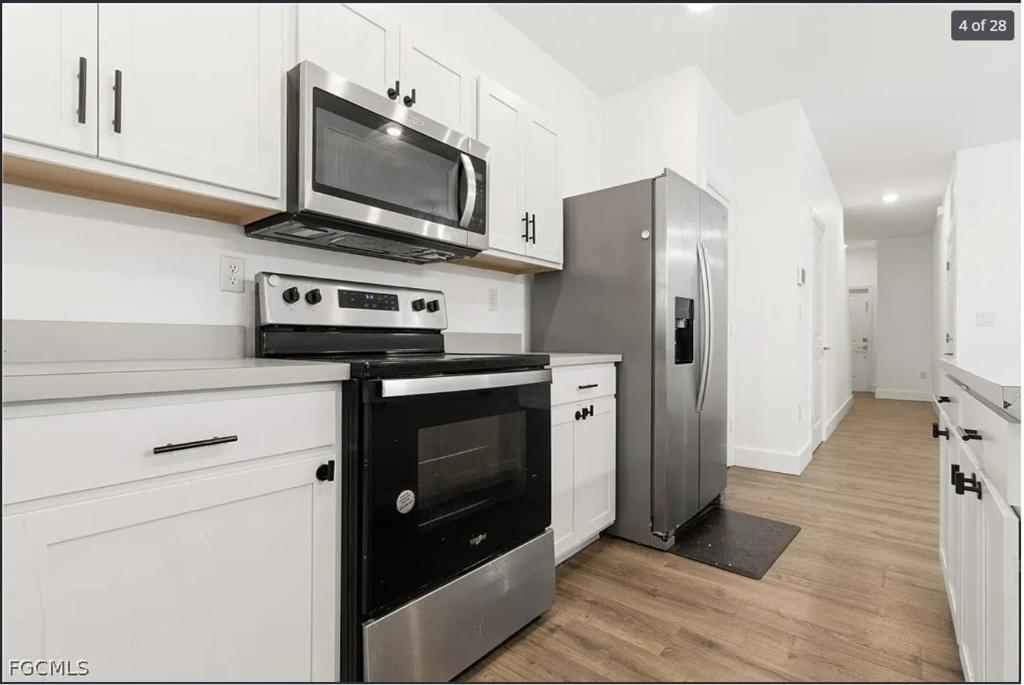 a white kitchen with a microwave and a refrigerator at Casa Lux in Florida City