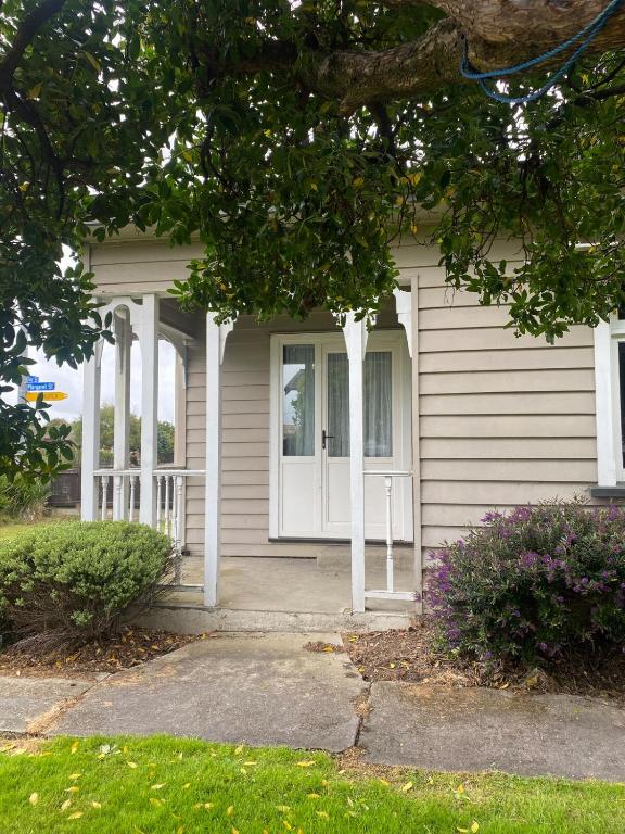 a white house with a porch and a window at Marvellous on Maggie in Invercargill