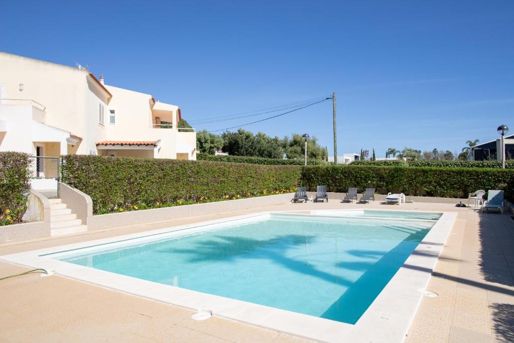 a swimming pool with chairs and a house at Sun & Salt Villa in Alvor