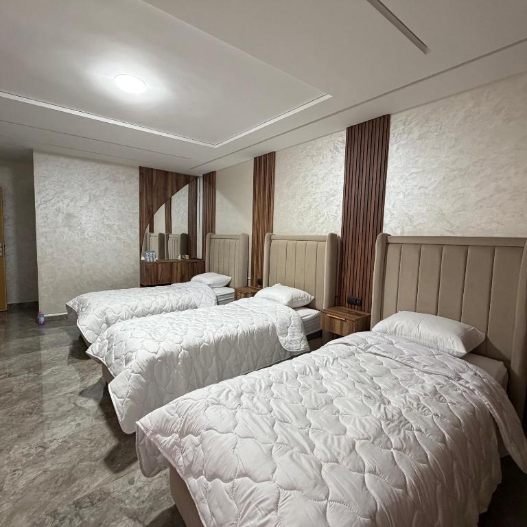 three beds in a hotel room with white sheets at Chambre Triple Séjour Confortable à Berkane in Berkane