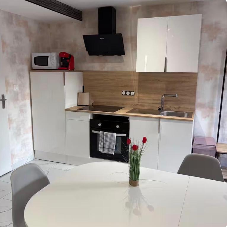 a kitchen with a table with red flowers on it at Logement centre ville in Saint-Dizier