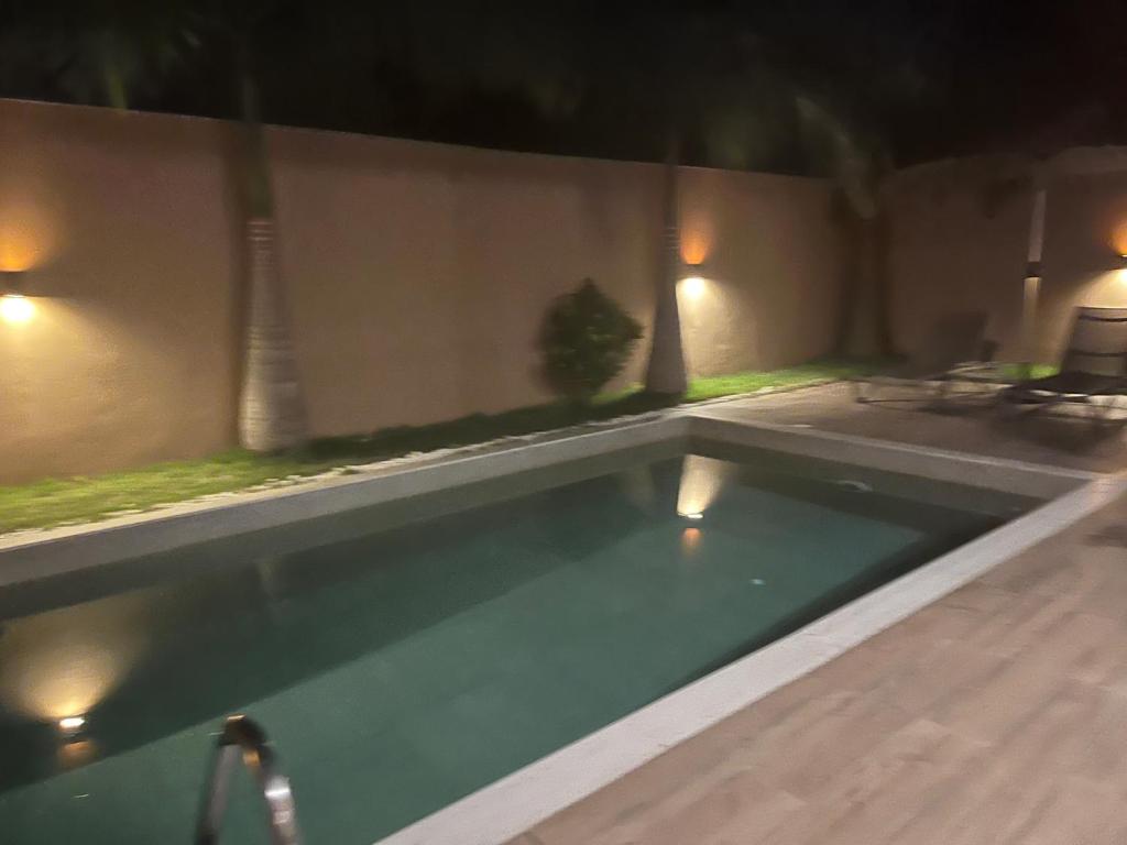 a swimming pool in a backyard at night at Villa Abou in Assinie