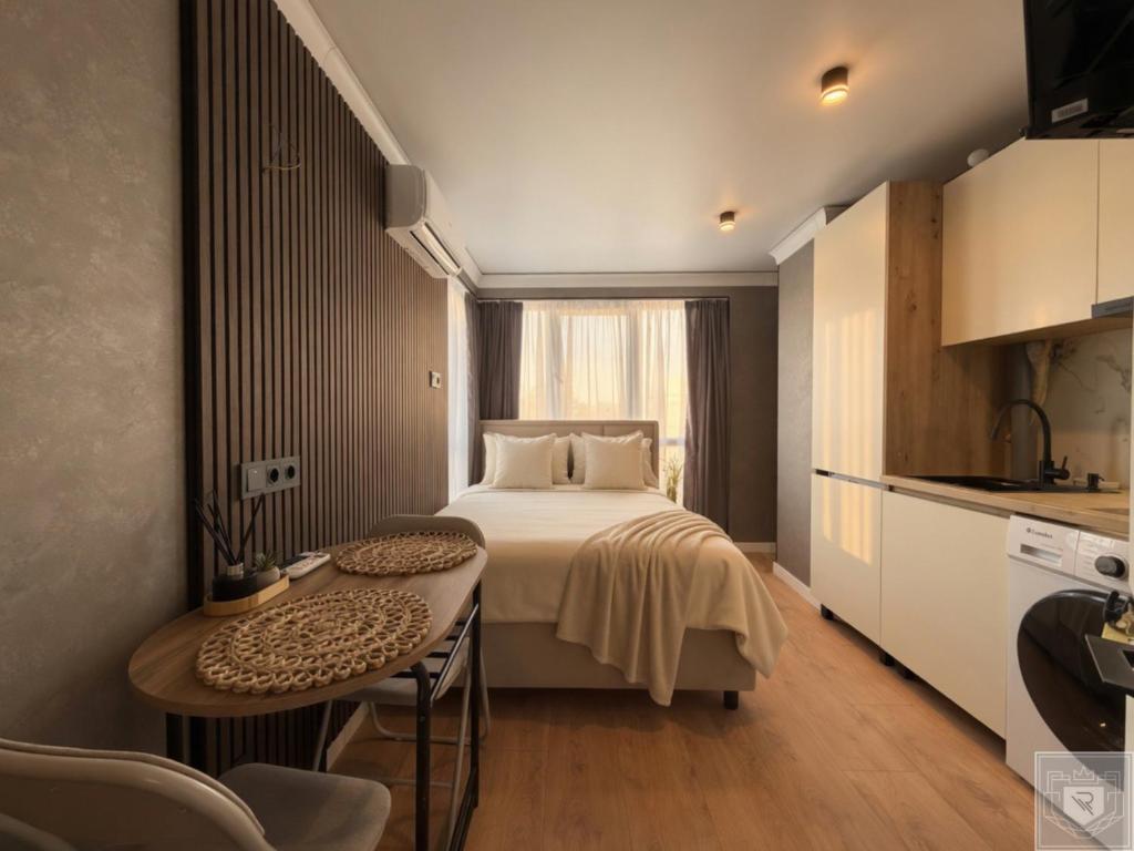 a bedroom with a bed and a table and a kitchen at RentHouse Apartments Panoramic-Airport-Studio in Chişinău