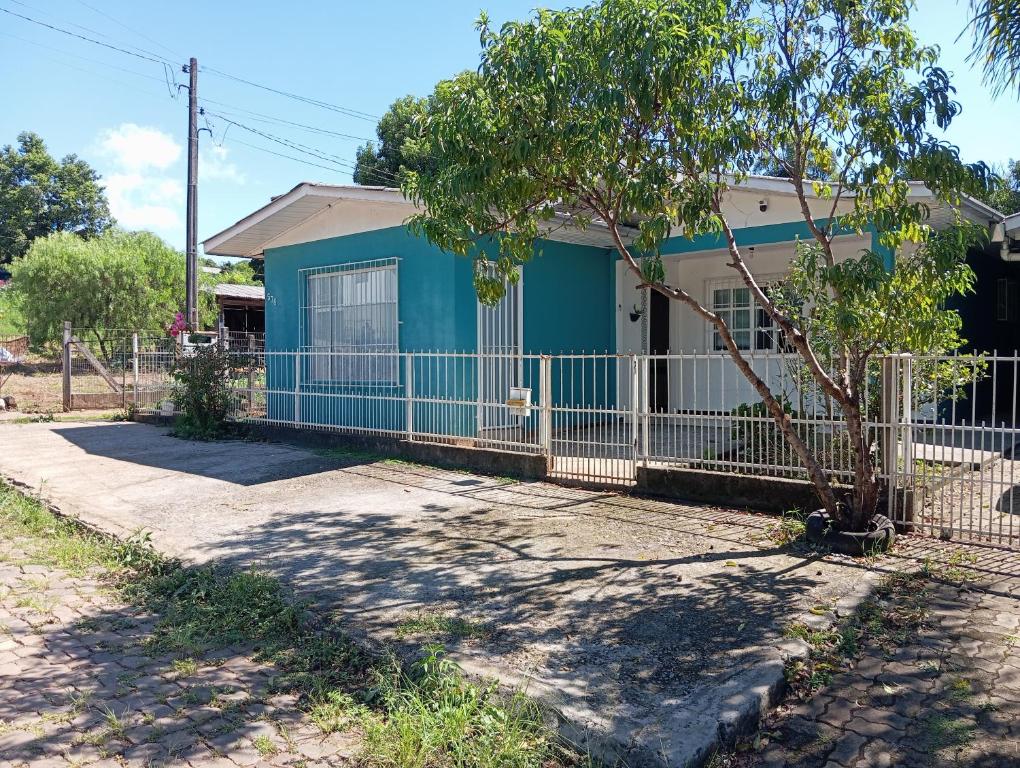 a blue house with a fence in front of it at Ampla acomodação e com ótimo localização in Machadinho