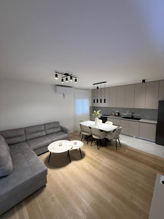 a living room with a couch and tables and a kitchen at Apartman Royal in Posušje