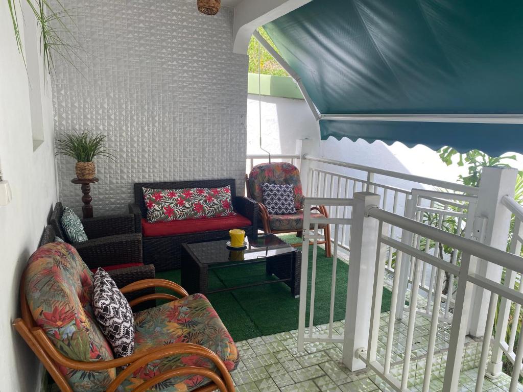 a balcony with a couch and chairs on a porch at Bleu Ocean in Deshaies