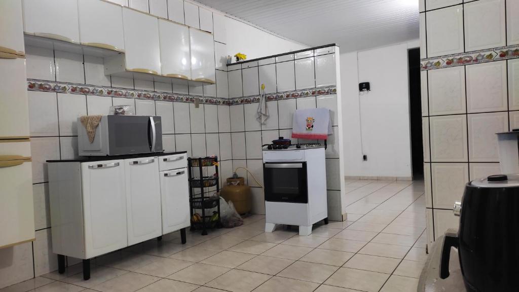 a kitchen with white tiled walls and white appliances at Quarto em Casa Completa no Centro de Ilhéus in Ilhéus