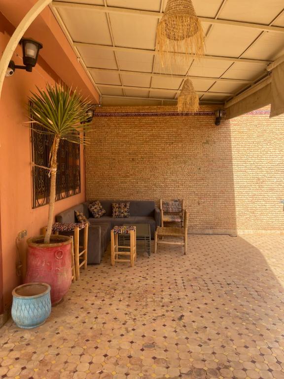 a living room with a couch and a palm tree at Ferme agafay in El Karia