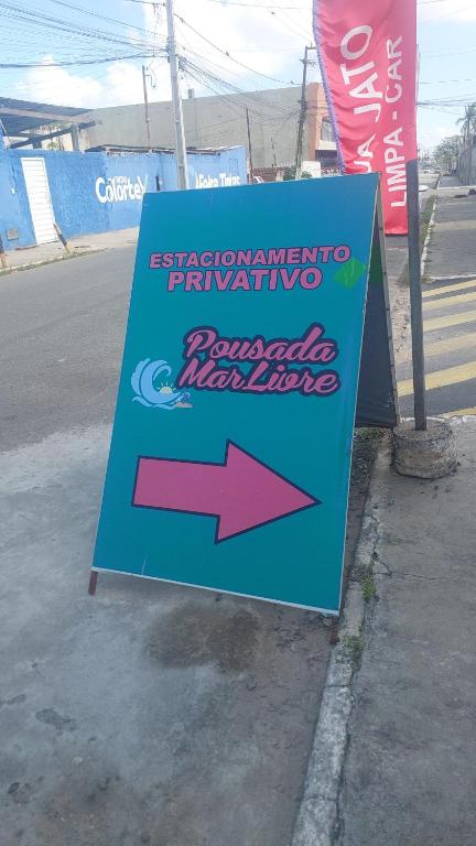 a sign on the side of a street with an arrow at pousada mar livre in Aracaju