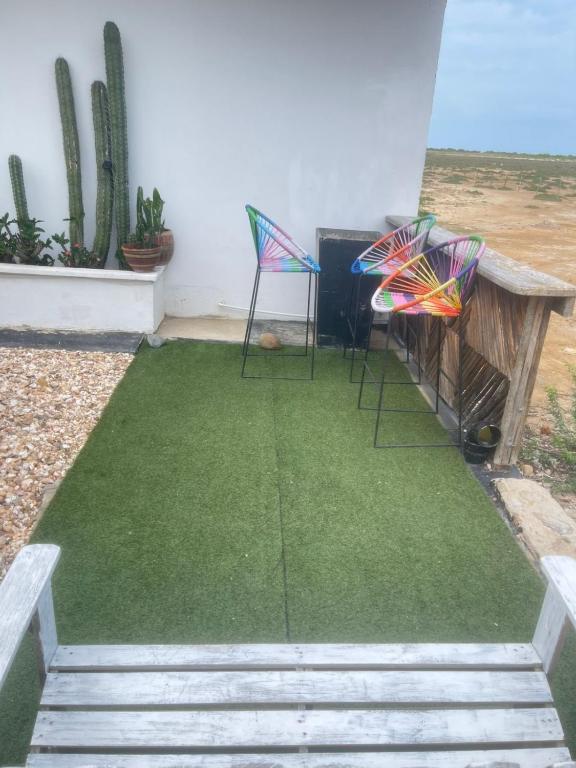 a patio with two chairs and a table and grass at Bora Bora Hostal y Pasadías in Manaure
