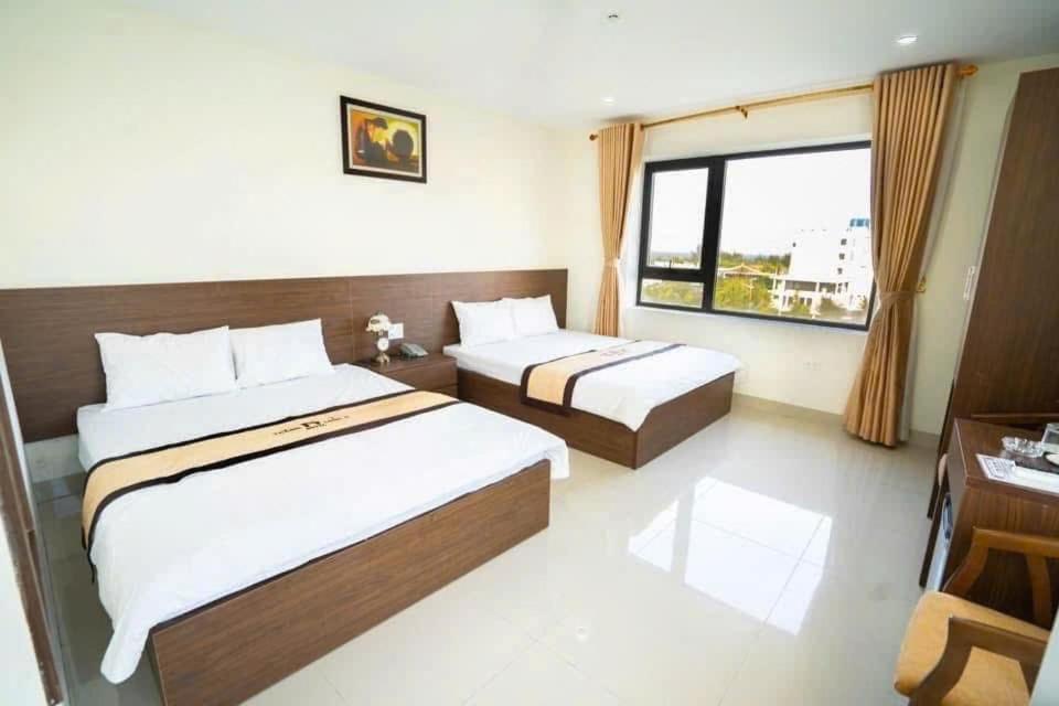 a bedroom with two beds and a desk and a window at Khách Sạn Thăng Long 2 in Sầm Sơn