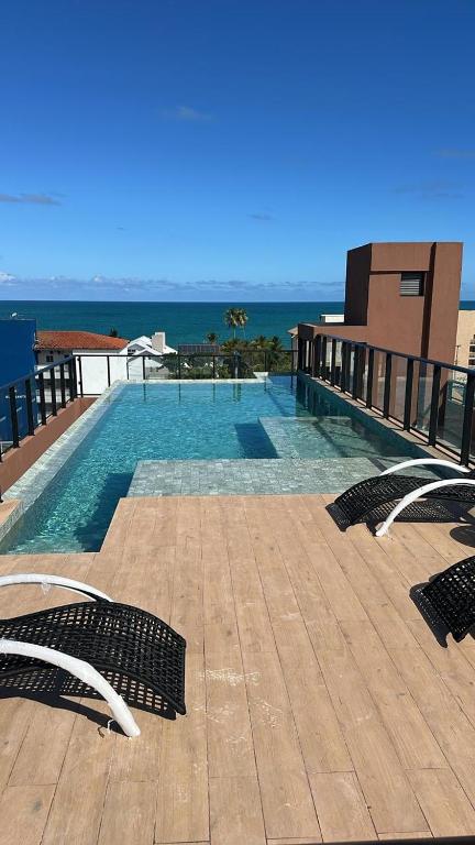 a swimming pool with chairs and the ocean in the background at Carneiros Pernambuco in Tamandaré