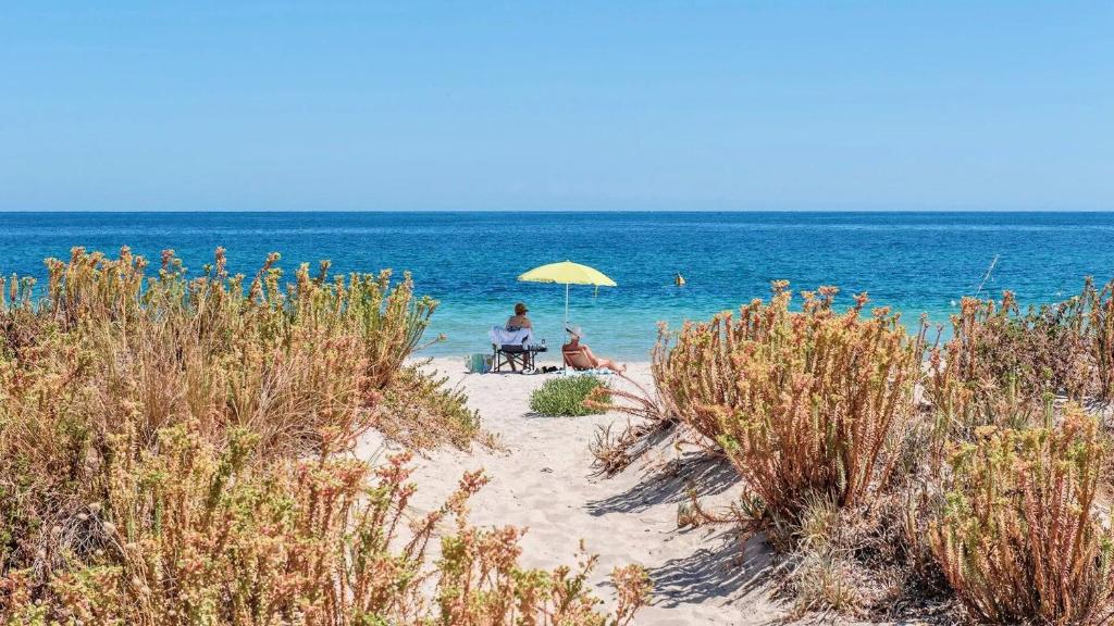 two people sitting under an umbrella on the beach at Escape to 39 at Cape View in Busselton
