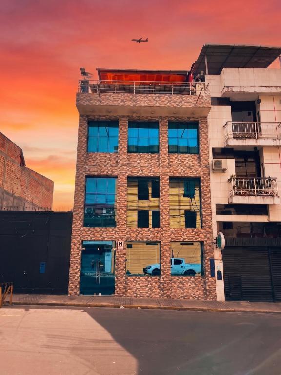 a tall brick building with a plane in the sky at Casa Nativa Iquitos in Iquitos