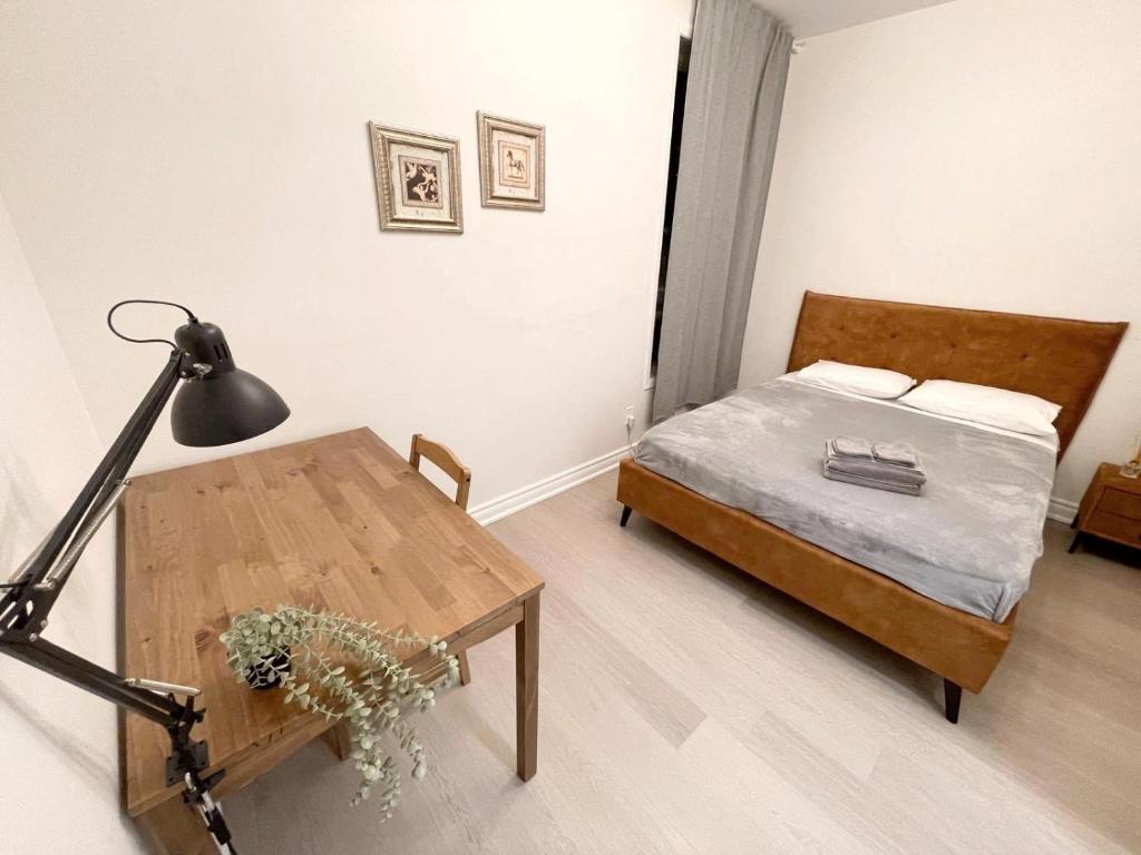 a bedroom with a bed and a table with a lamp at Queen Boutique Rooms in Toronto