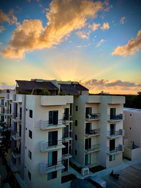 a white apartment building with a sunset in the background at 2 pools,long stays,peaceful complex,relax,WiFi,remote work,8mins drive to beach,casa Yellowstone in Puerto Morelos