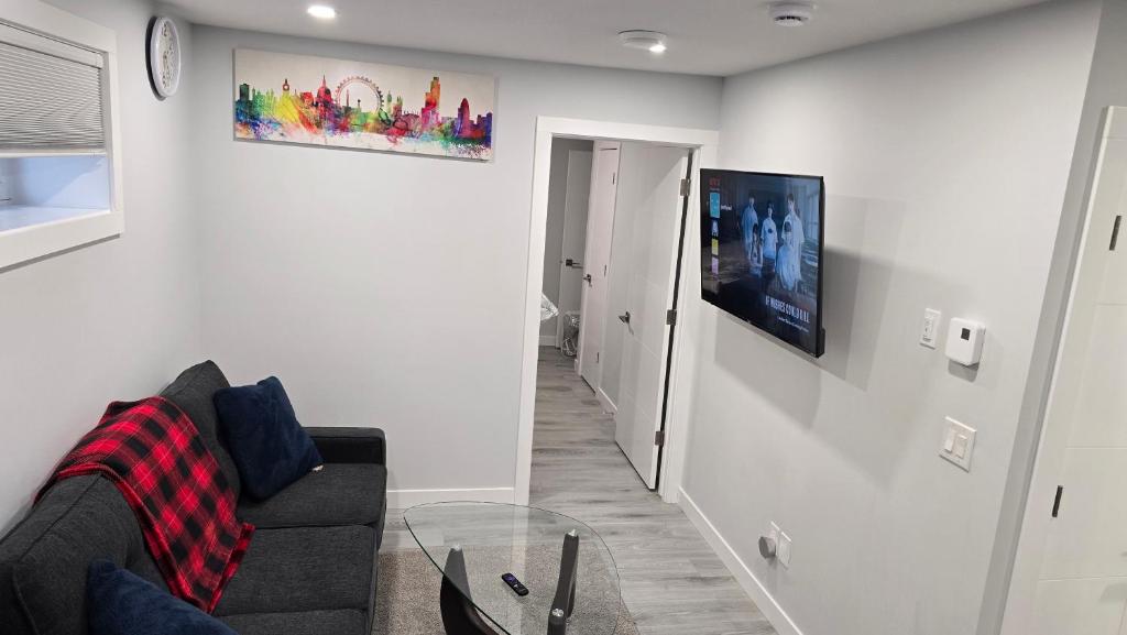 ein Wohnzimmer mit einer Couch und einem Fernseher an der Wand in der Unterkunft Koko Suites in Regina