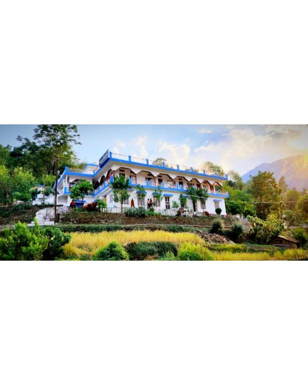 a picture of a large building with mountains in the background at Trance Himalaya in Gupta Kāshi