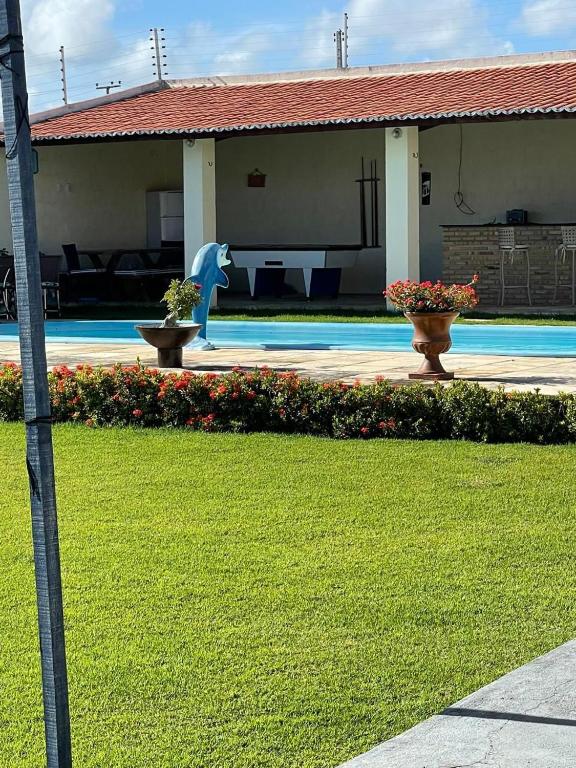 a house with a dolphin statue next to a pool at Casa de praia Morro Branco in Beberibe