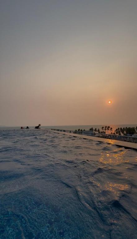 a beach with the sun setting in the horizon at The Patio See Sea 155 in Ban Bang Saen (1)
