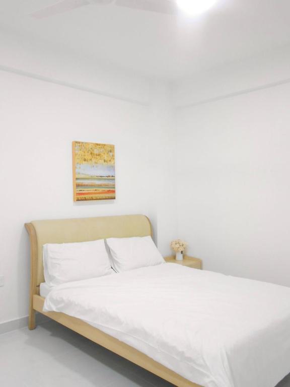 a bed with white sheets and a painting on the wall at Bougainvillea Breeze in Male City