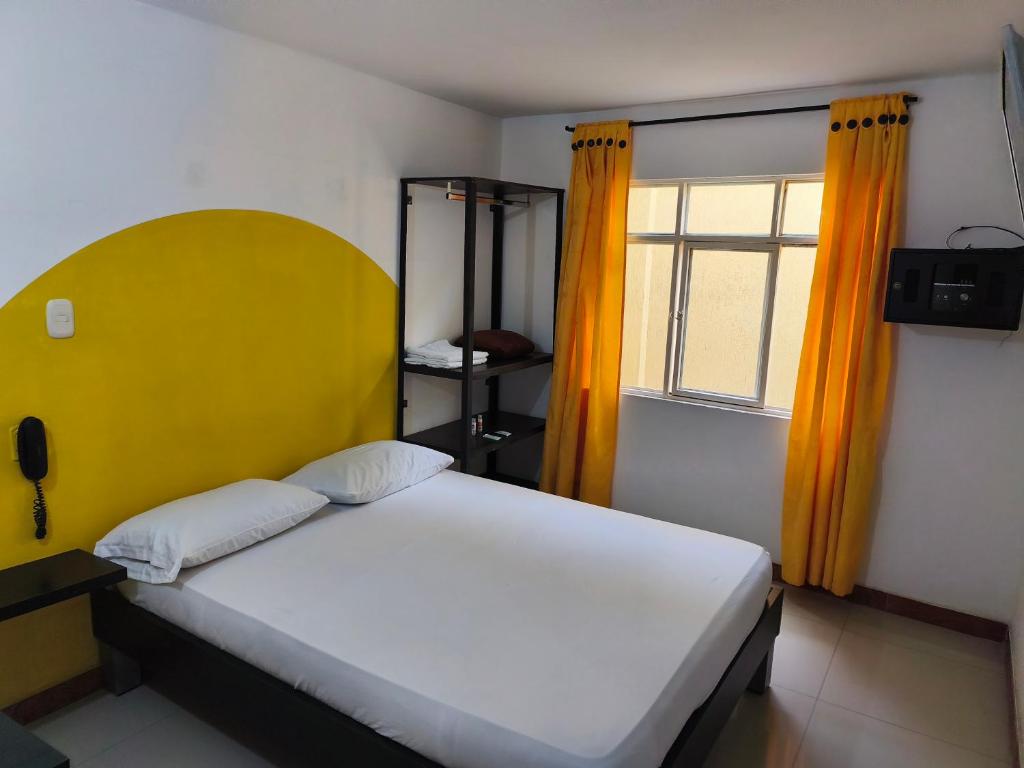 a bedroom with a bed with a yellow headboard and a window at Hotel Cielo de Tambores in Cali