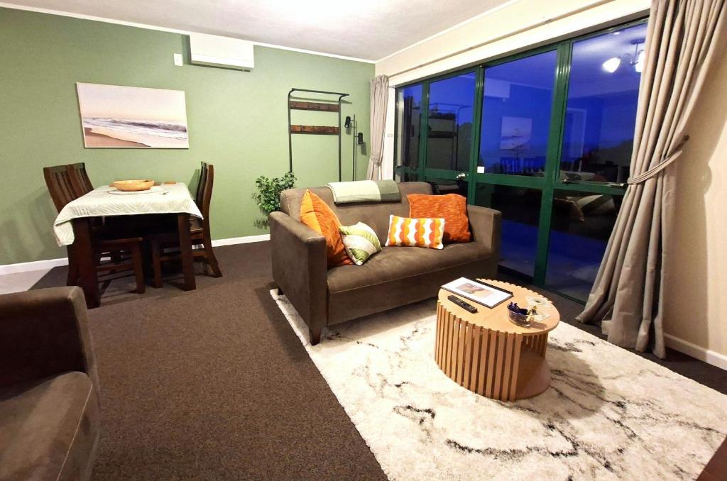 a living room with a couch and a table at 2-bedroom harbour view apartment with parking, 8 mins to Dunedin in Dunedin