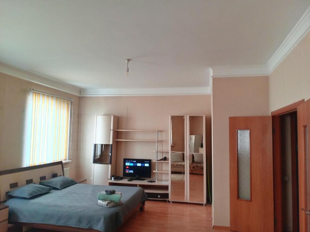 a bedroom with a bed and a flat screen tv at Абай2 103 in Astana
