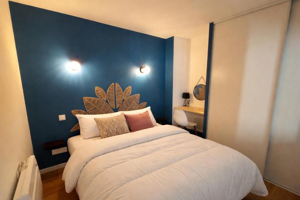 a bedroom with a large bed with a blue wall at Appartement Centre in Lourdes