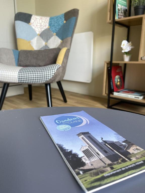 a book sitting on a table next to a chair at Studio charmant avec terrasse privée in Oradour-sur-Glane