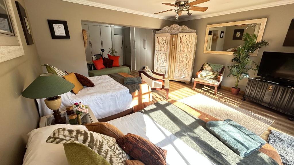 a living room with two beds and a television at Artzy's Garden View 1km to Olivedale Clinic in Northriding