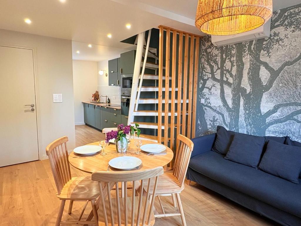 a dining room with a table and a blue couch at L'Adresse - Rempart Sud - Eguisheim avec garage privé in Eguisheim