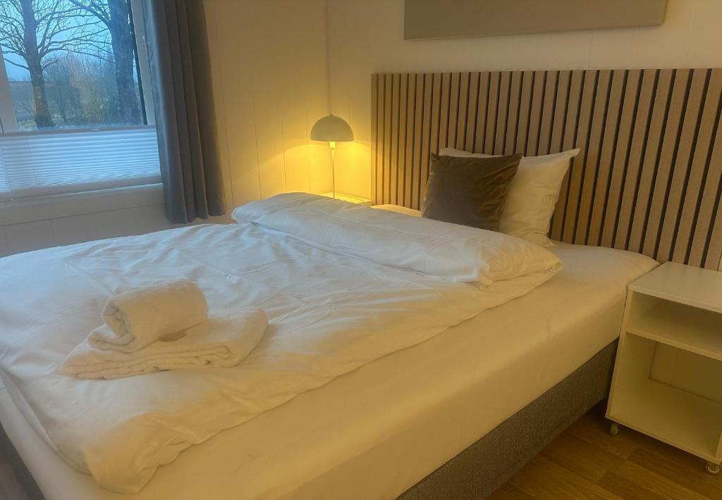 a bed with white sheets and towels on it at Selvbetjent leilighetshotell på Ålgård in Ålgård