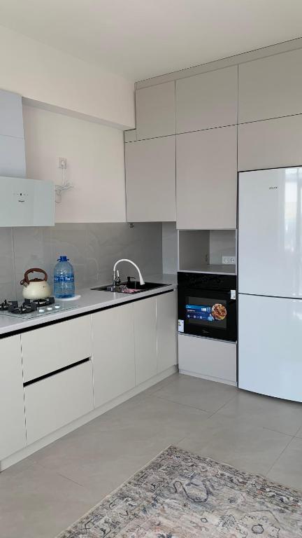a white kitchen with a sink and a refrigerator at Cosmos in Tashkent