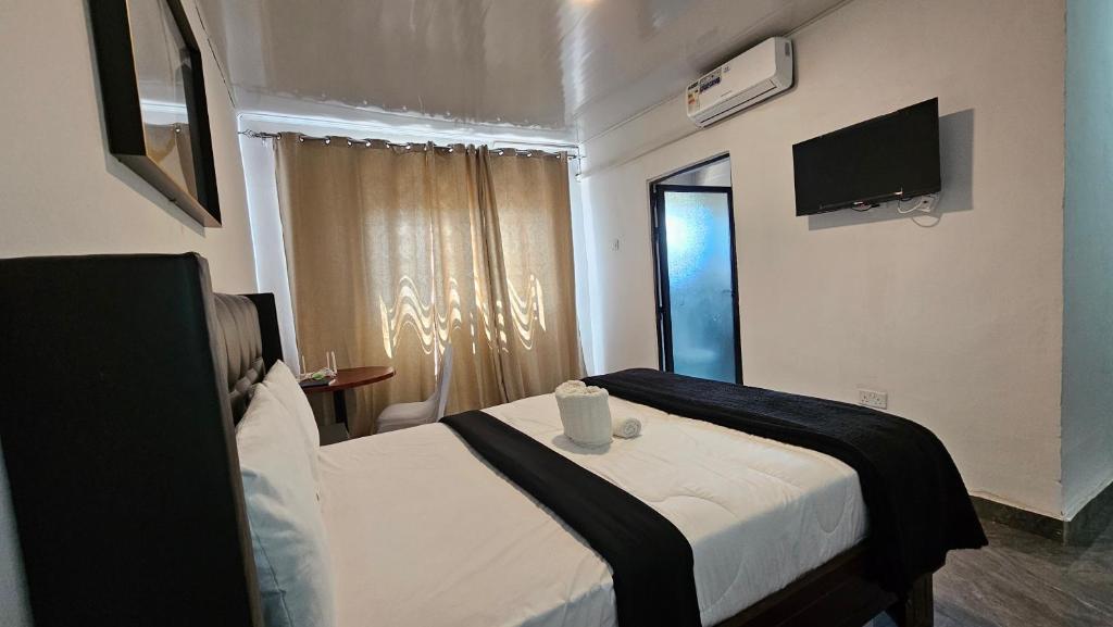 a hotel room with a bed and a television at Malbon Green Executive Plus Lodge in Kafue