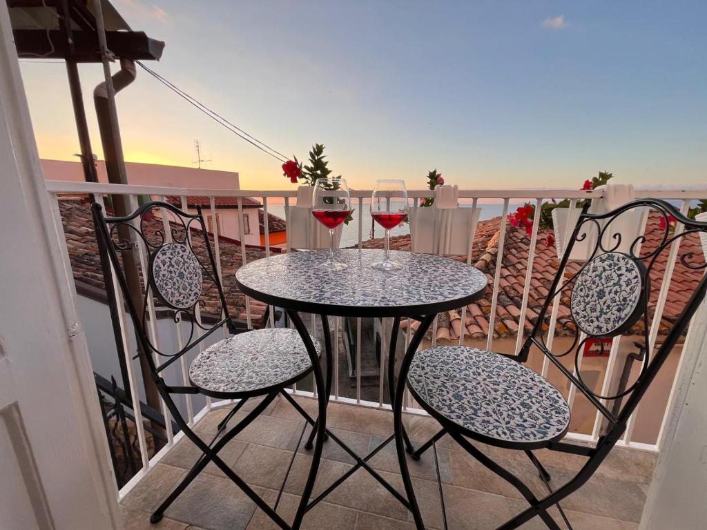 a table with two glasses of wine on a balcony at Ondablurooms1 in Pizzo
