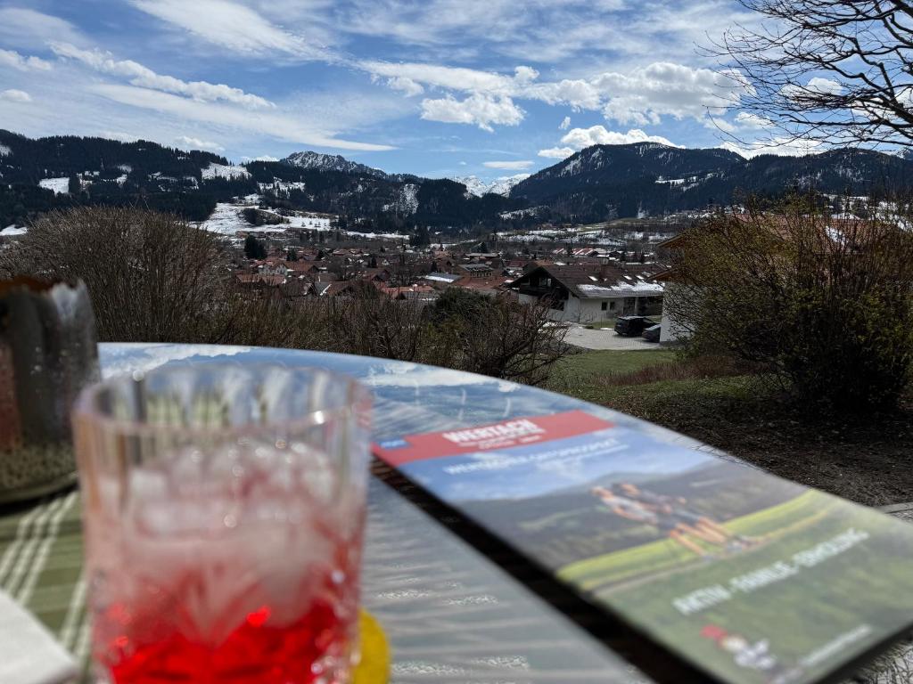 a glass sitting on a table with a view of a city at "Unter Freunden", Design Meets Allgäu in Wertach