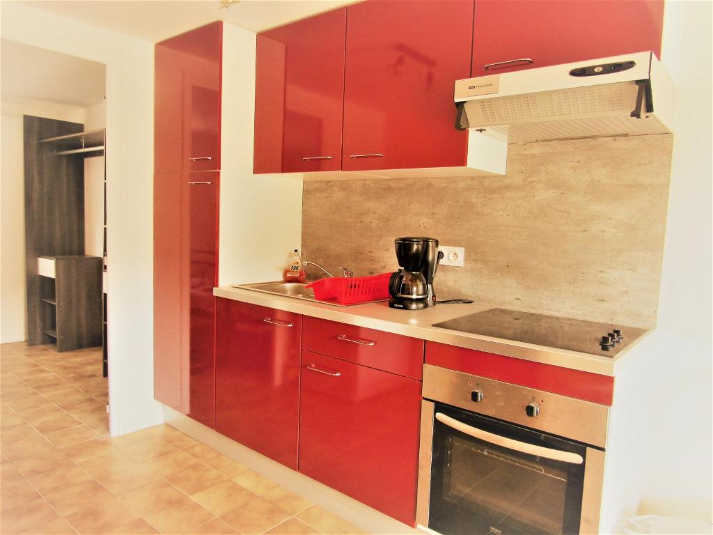 eine Küche mit roten Schränken und einem Kamin in der Unterkunft LA ORANA in Frontignan