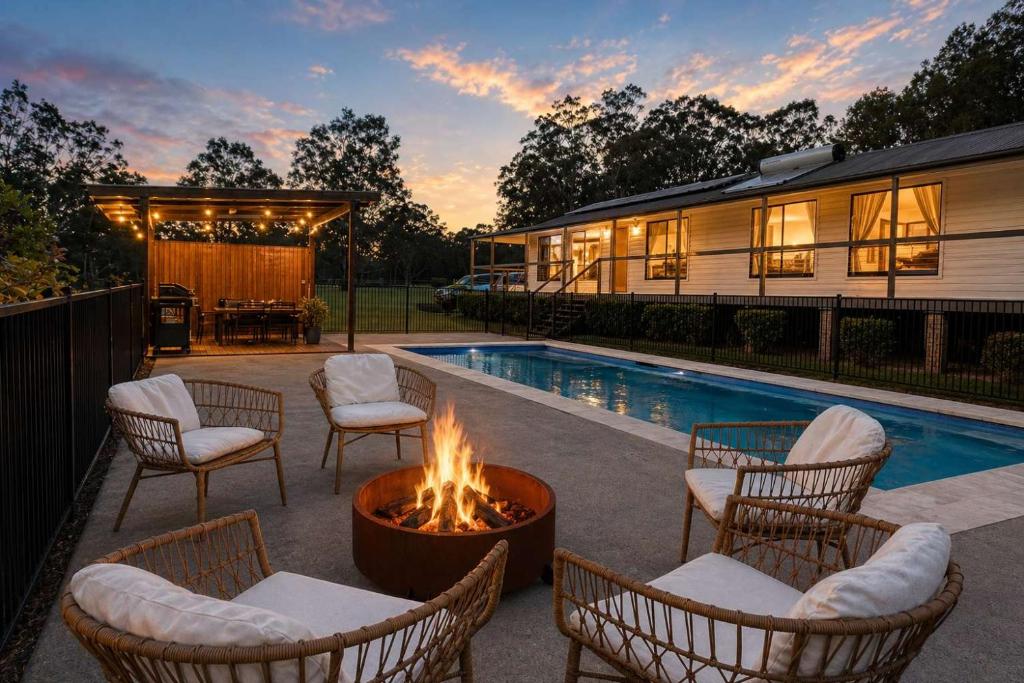 a patio with chairs and a fire pit next to a pool at Chardonnay Escape in Pokolbin