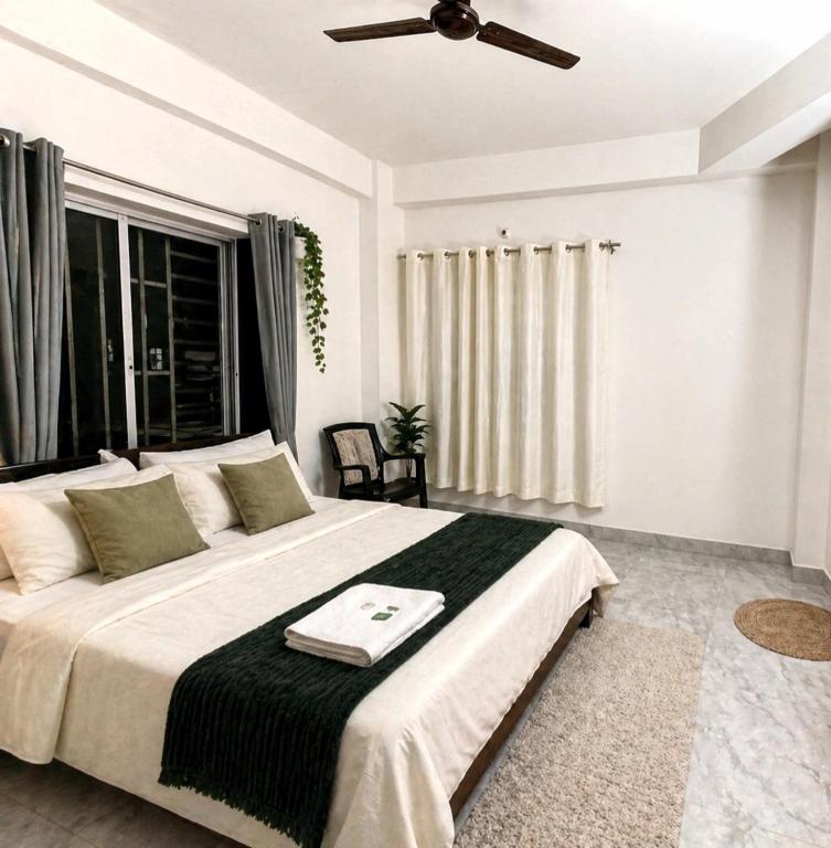 a bedroom with a large bed with a ceiling fan at The Travellers Nest in Siliguri