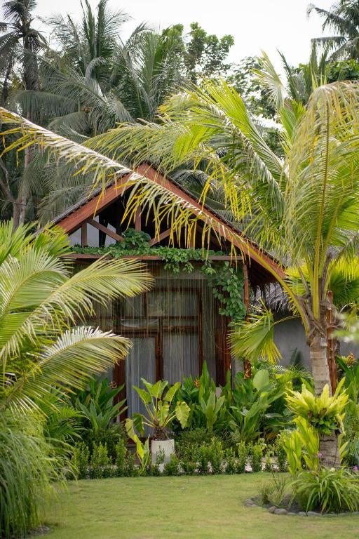a resort with palm trees in front of a building at The Salty Jungle in Cijulang Nusawiru Airport
