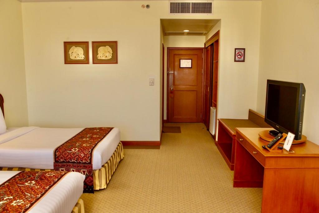 a hotel room with two beds and a flat screen tv at CS Pattani Hotel in Ban Ru Sa Mi Lae