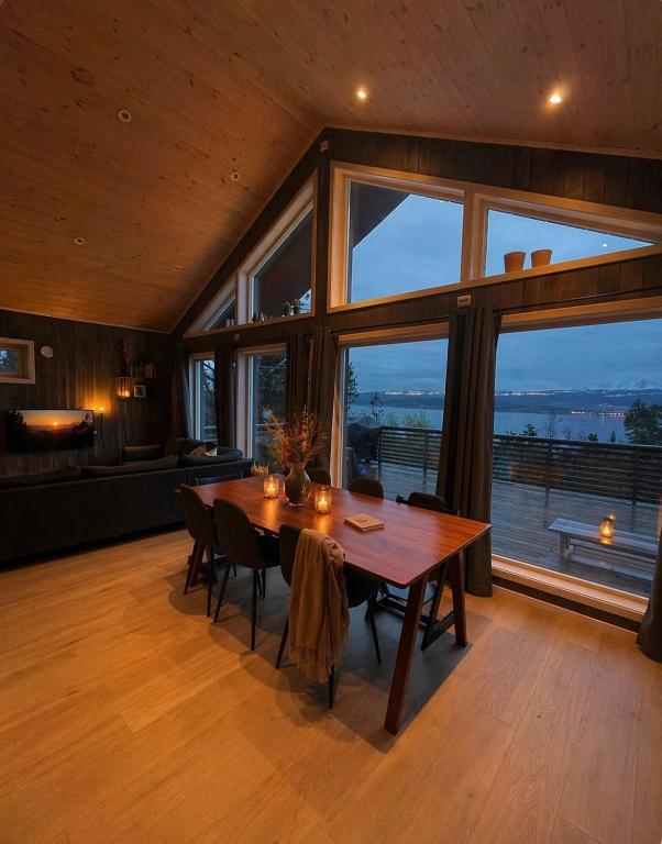 a dining room with a table and large windows at Modern chalet in Malangen in Mestervik