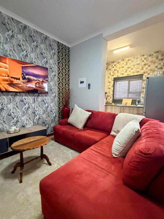 a living room with a red couch and a table at The Well Apartments in Mbabane