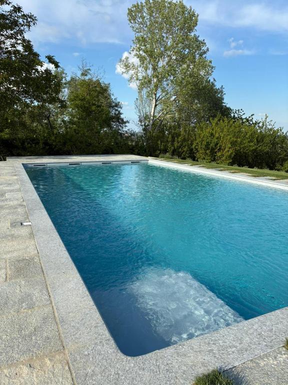 a swimming pool with blue water in a yard at Lungamerenda in Costigliole dʼAsti