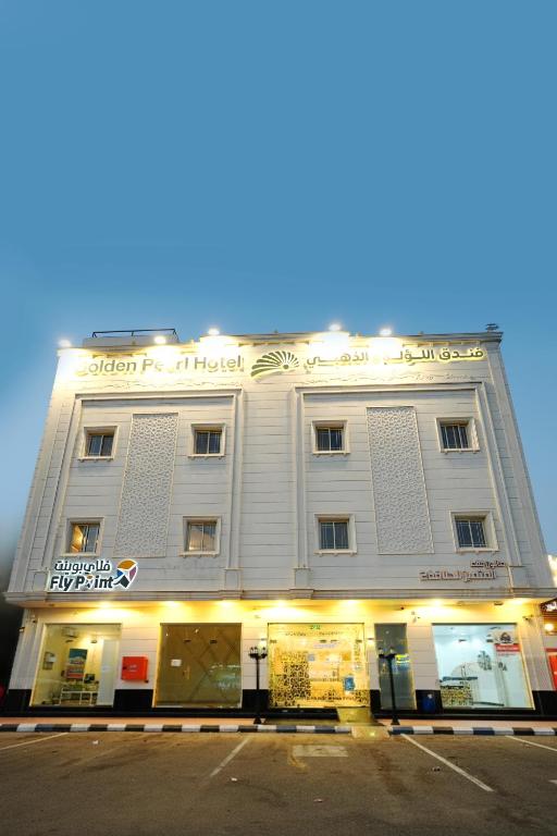 a large white building on a street corner at شقق اللؤلؤة الذهبي - Golden Pearl Apartments in Sīdī Ḩamzah