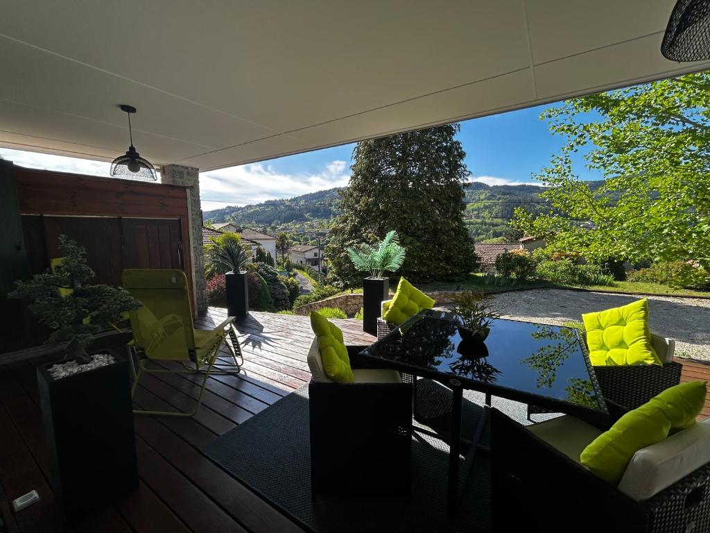 a screened in porch with a table and yellow pillows at Chambre d'hôtes de la Riaille 400 m de la dolce via in Le Cheylard