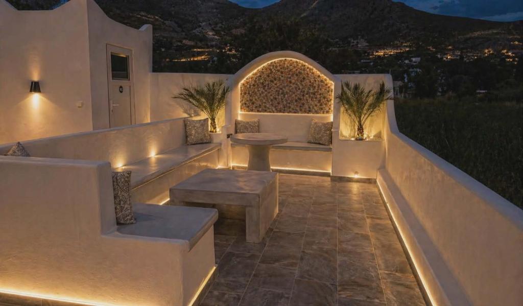 a patio with a bench and a table and lights at Papafotis Apartments & Suites in Alinda