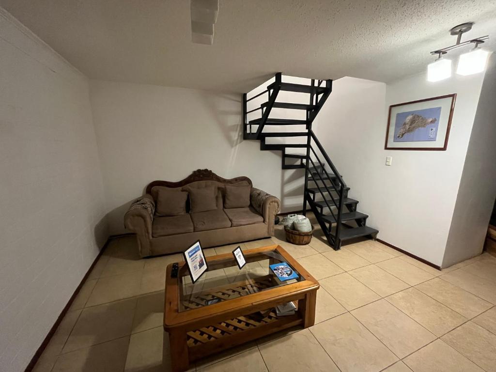 a living room with a couch and a spiral staircase at Casa cerca del Aeropuerto - Tu Espacio RE in Santiago